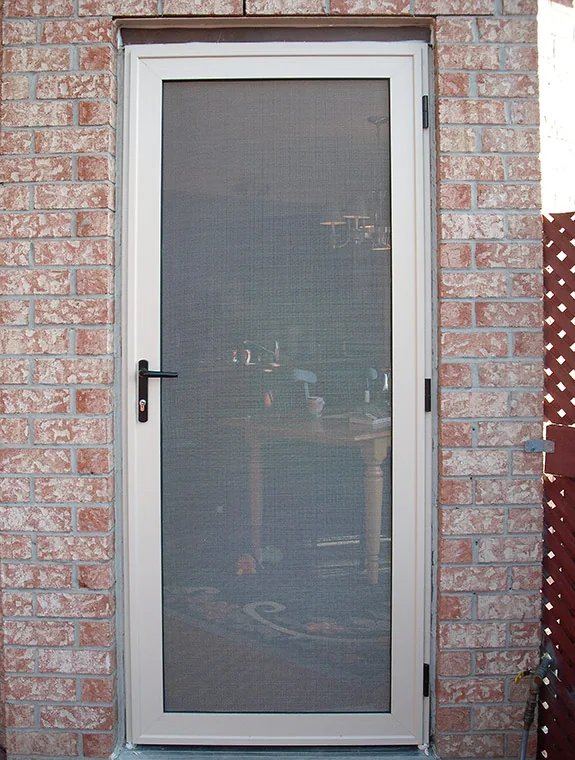 Beige security screen door installed on a brick house, blending in with the home's exterior