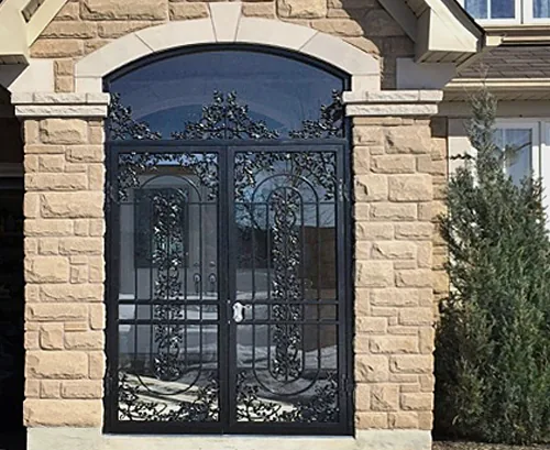 Ornate double security doors installed on a stone porch entrance of a home